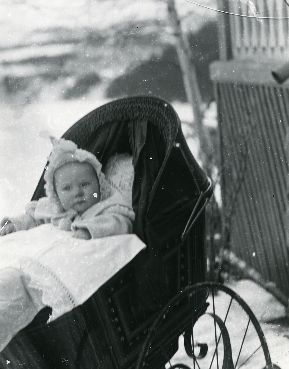 Spedbarn i barnevogn, ved veranda