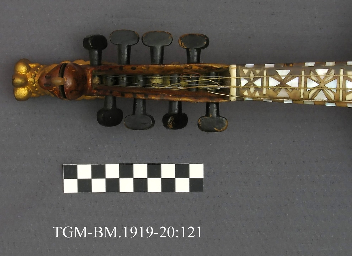 Fra protokollen: Hardingfele av den eldre, smale typen. Bruleggjingi stjerneforma, raud ferniss, stillepinnar og hovud spm vane (Hovudet nygylt). Paa merklappen inni stend: Fabrikeret af Erik Johnsen Helland i Bøe 1838. (Aarstalet ber merke av aa vera retta, serleg seinste siffer; papiret under aarstalet er vekkskrapa og talet uppnya paa berre treet.). Lok av gran, trojsk av hegg, botn av svartor, hovud av bjørk.