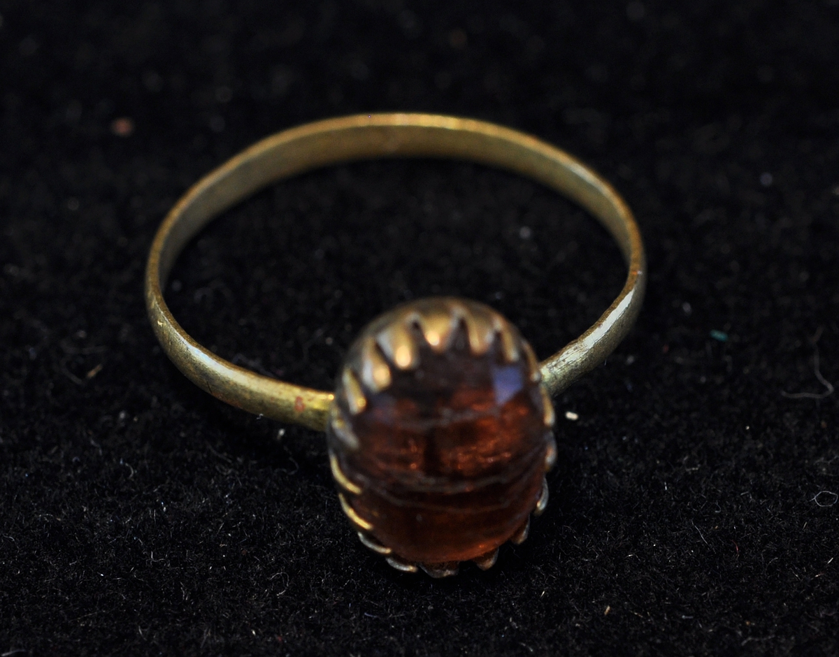 Liten ring, muligens av gull, med innfattet sten (sanns. rav.)