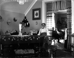 Interiør med kvinne, to menn i bakgrunn