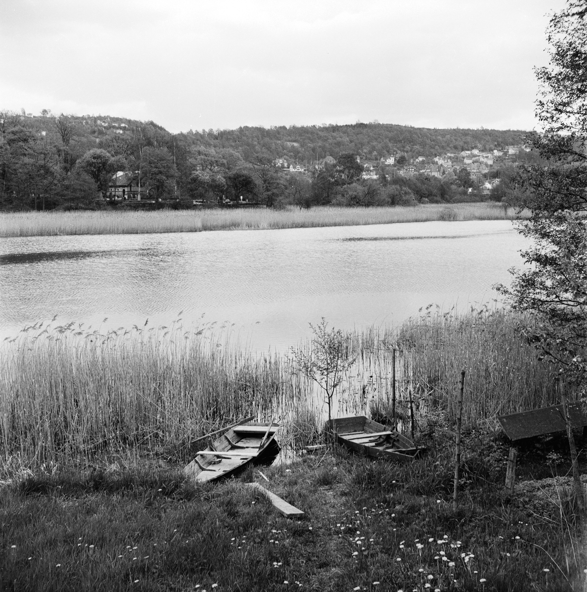 Kavasjön i Huskvarna. Vid stranden ligger två roddbåtar och andra sidan sjön skymtar kyrkan.