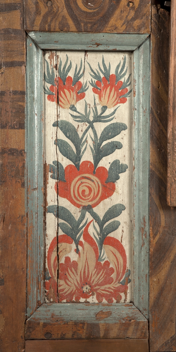 Målat hängskåp av furu. Dörrspegeln marmorerad i gråblått och vitt. Sidorspeglarna dekorerade med flamtulpaner i rött, gråblått på vit grund. Ljusblå listverk. För övrigt brun ådring. Över dörren märkt: A o 1789 IMS D 17 APR.
