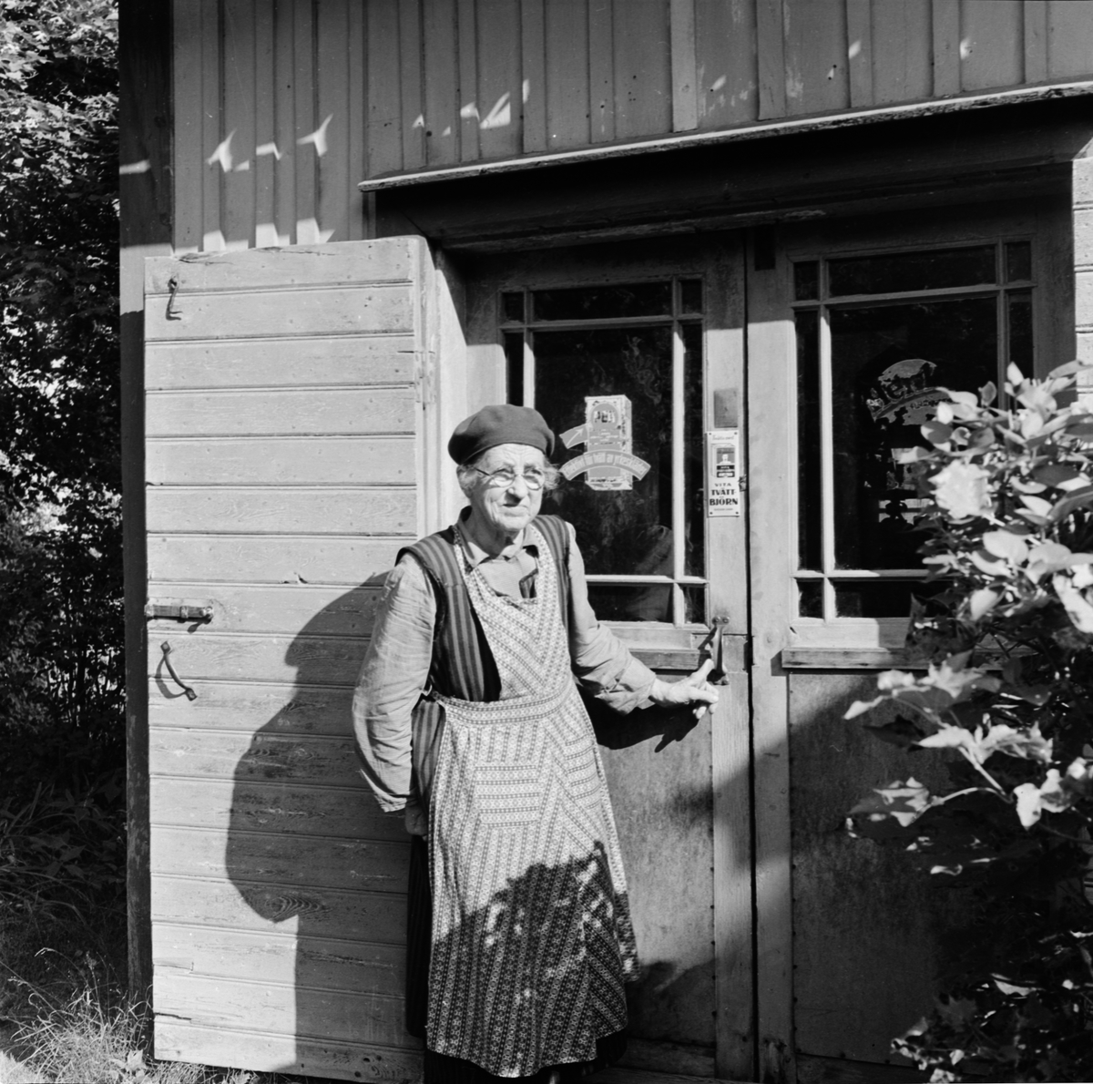 Kvinna vid butiksdörren, Svinnegarn socken, Uppland