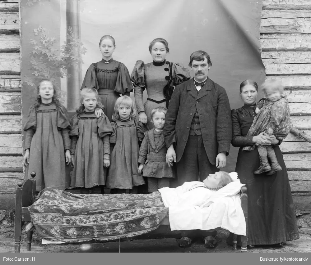 Fmailiegruppe ved en båre.
Hr. Talbø ved sin avdøde datter og sine 7 barn