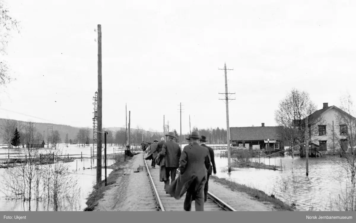 Flommen i 1934 : vannet nærmer seg jernbanelinjen i Østerdalen - reisende til fots forbi bruddstedet?