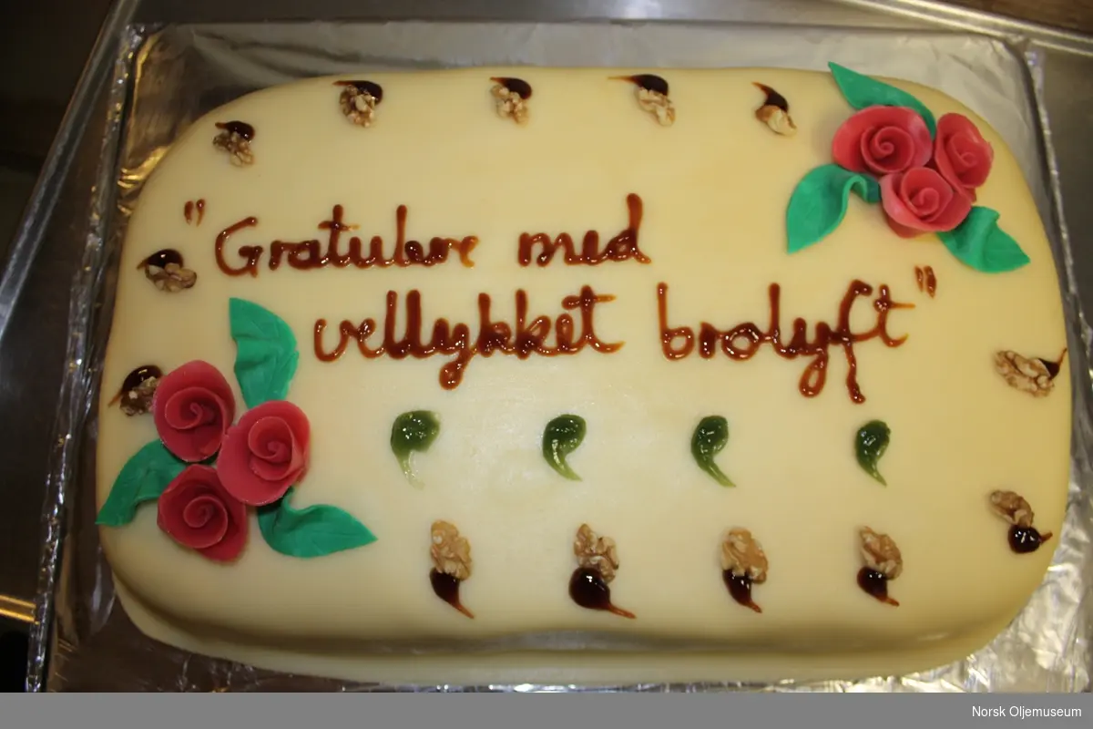 Kake med dekorert marsipanlokk med teksten  "Gratulere med et vellykket brolyft" i anledning et vellykket broløft på Valhallfeltet.