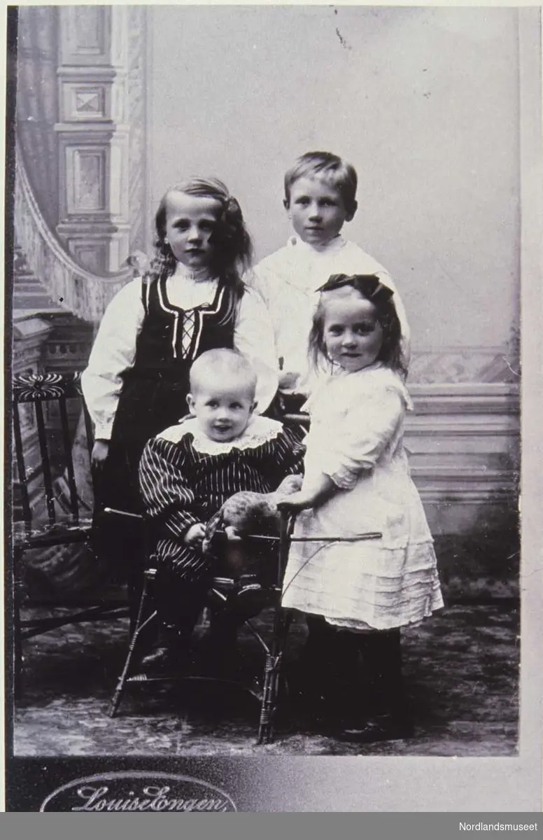 Bildet viser bl.a. Anne Stue Aanesen nederst til høyre 4 barn, en gutt og to jenter stående, samt en baby sittende i en stol foran. Navnene på dem er ellers: Oskar, Valborg og Viktor. Finnes også som repro på lysbilde.