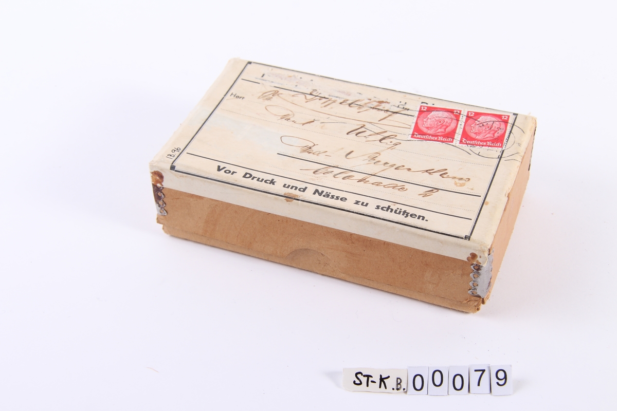 Pappeske med frimerker og håndskrevet adresse. Innholder tretti små sommerfugler av malt porselen.