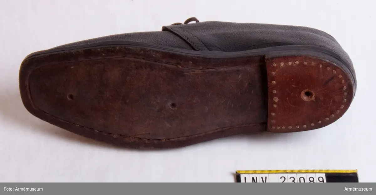 Grupp C I.
Skor av brunt läder. En av skorna har rött lacksigill.

Vidhängande lapp på ena skon med text: "För Artillerimuseum, Beställer en sko lika detta prof. Obs. Mycket brådtom."
