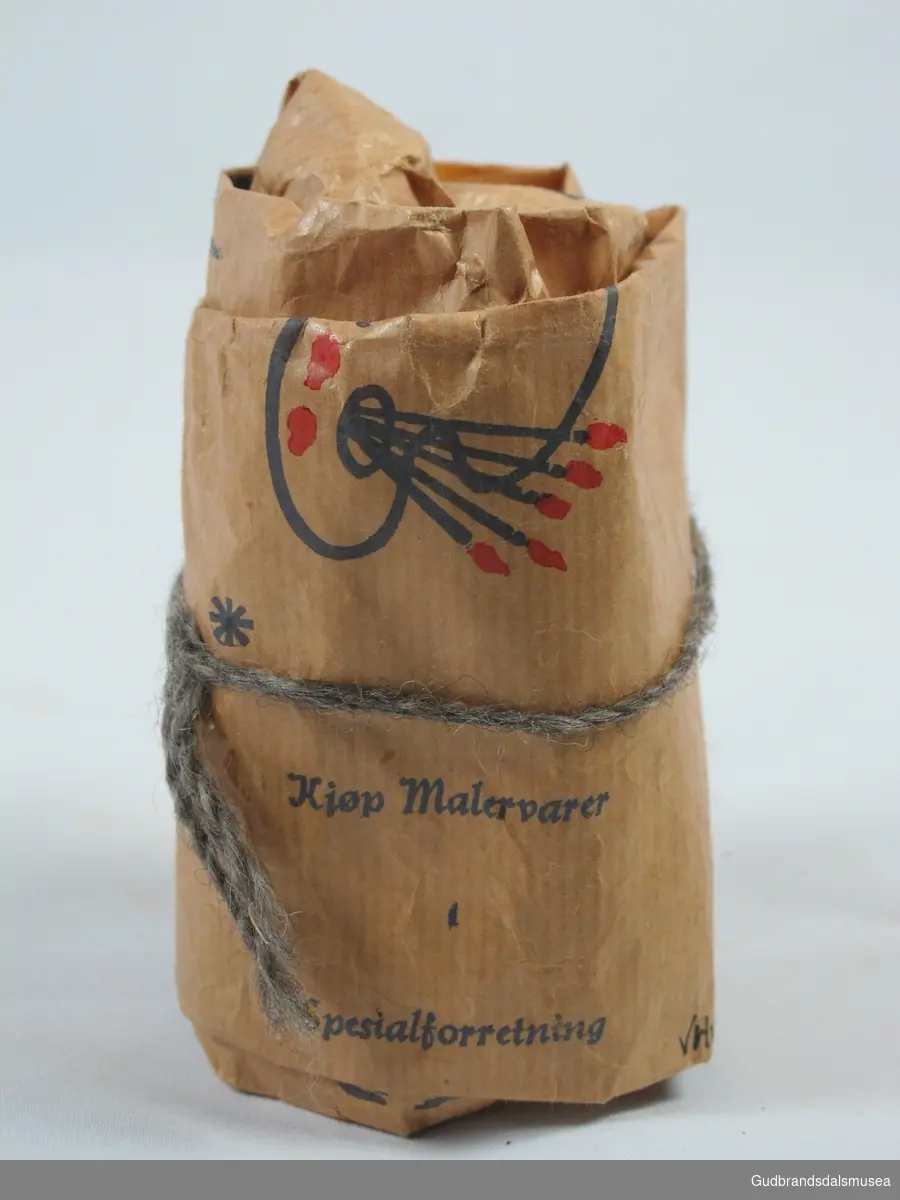 Papirpose med innhold fra Tidl. J.H.Bøhmers Eftf.
Posen har motiver i rødt og blått :
Malingspann i rødt og blått, blå palett med røde malingsklatter, blå pensler med rød bust.
Pakken er knyttet igjen med grå og sortspettet ulltråd.