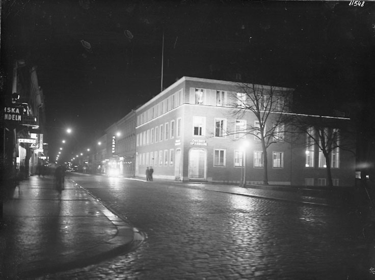 Stadsvy, Drottninggatan söderut, bostadshus med affärer i gatuplanet.
Örebro Sparbank till höger på bilden.
Bilden tagen på natten.
