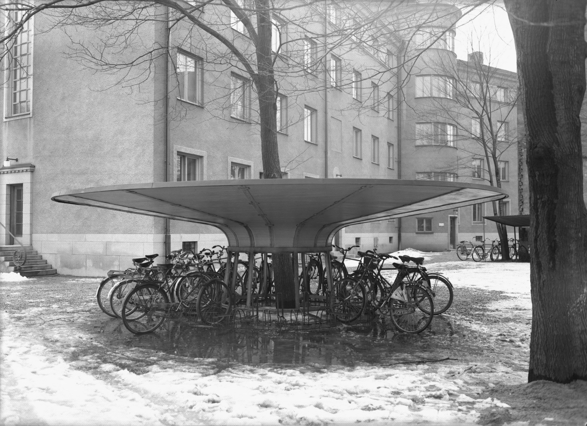 Cyklar i cykelställ vid kortänden av Nämndhuset ut mot Vasagatan. 
Nämndhuset har adress Vasastrand 11-13 och är ett kontorshus. 
Byggnadsnämnden.