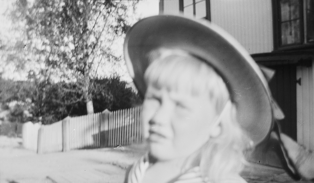 Iacob med sommerhatt på hodet fotografert på gårdsplassen utenfor et hus.