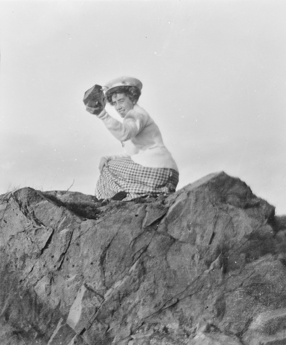 Celina Ihlen Mathiesen sitter på huk på noen spisse berg og holder opp en stein.
