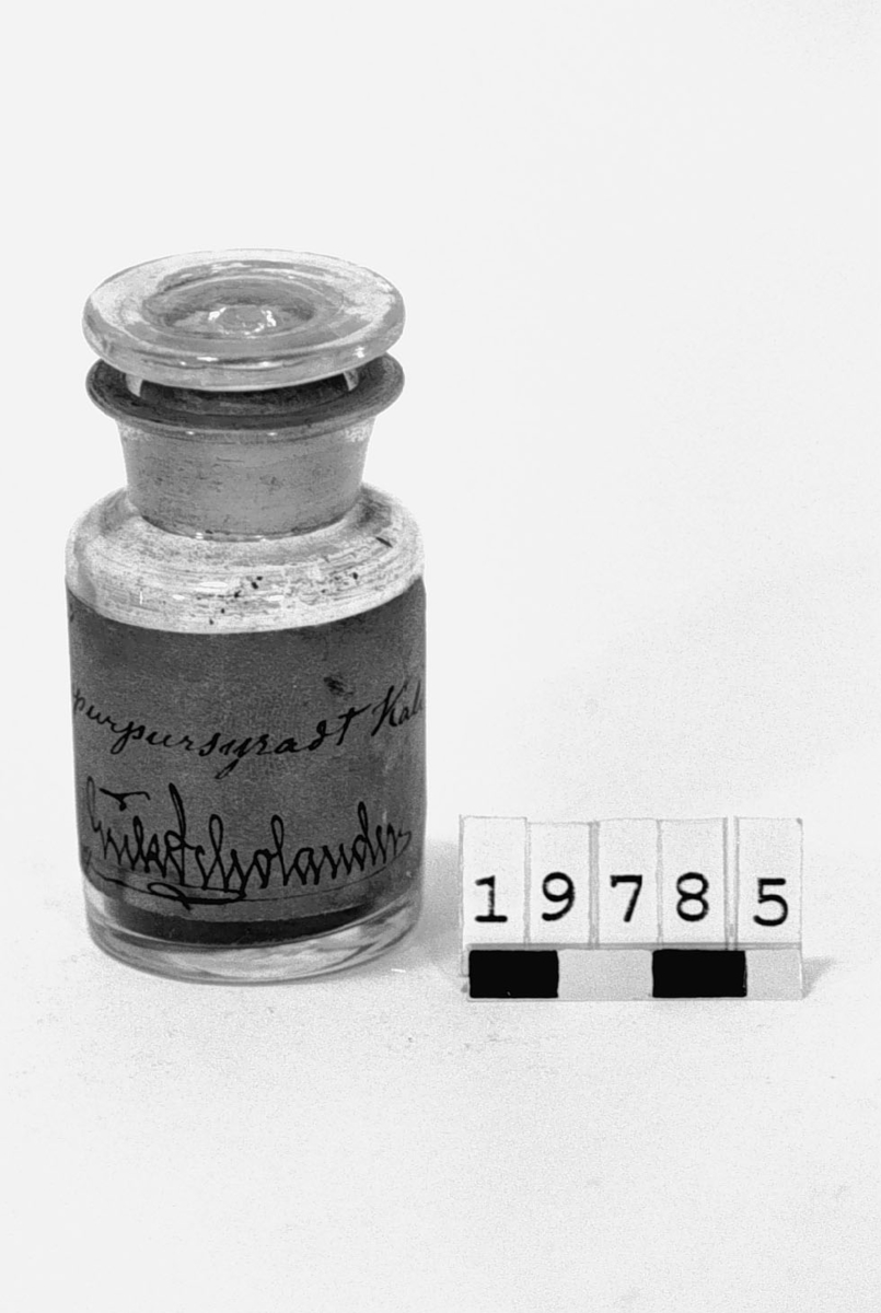 Prov på "Isopurpursyrat Kali. V.T. 1874. Erik Scholander", i burk av glas med etikett.