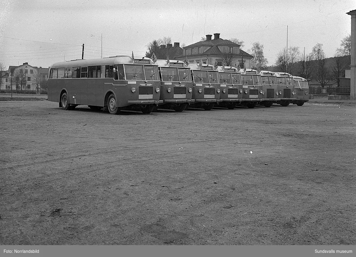Bussar uppställda på rad på Västra plan, där Åkersviksskolan numera (2016) ligger. Bakom bussarna syns bland annat Kronohäktet och Västra domsaga.