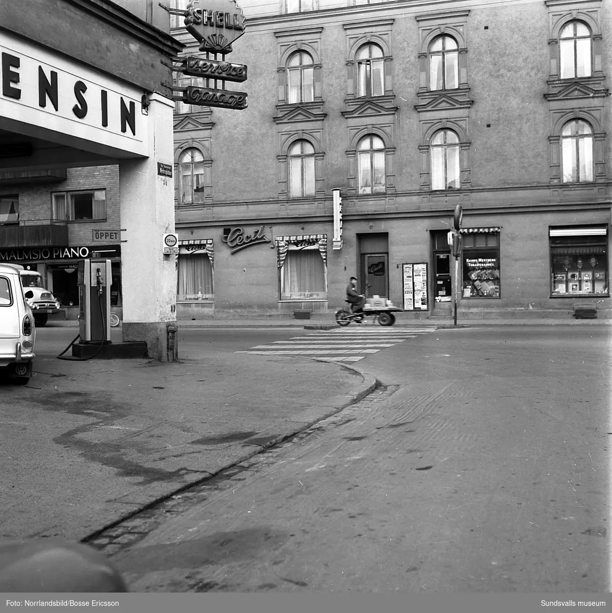 Gatuvyer i korsningen Köpmangatan-Nybrogatan med Shellmacken i hörnet, Cecil, Malmsjö piano med flera butiker.