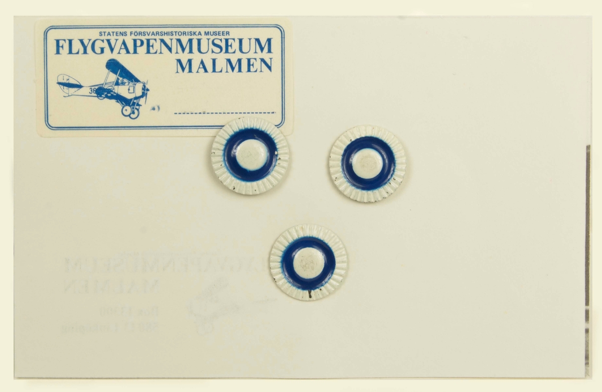 Mössmärken till Finska Armens uniform, avsedda för F 19 uniformer som ingår i FVM museets samlingar. Tre märken fästa på dubbelsidigt kort.