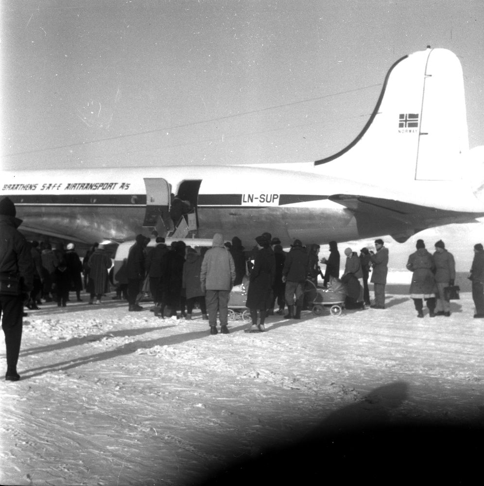 Lufthavn/Flyplass. Adventdalen/Svalbard. Et fly, LN-SUP, Douglas C-54B, Skymaster fra Braathens SAFE, har landet. Mange mennesker samlet rundt flyet.