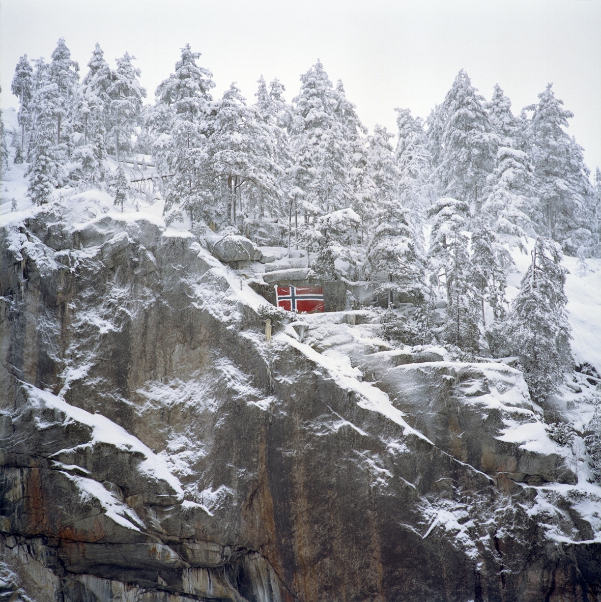 Motivet er av lettsnedekket fjellside med norsk flagg påmalt fjellsiden.