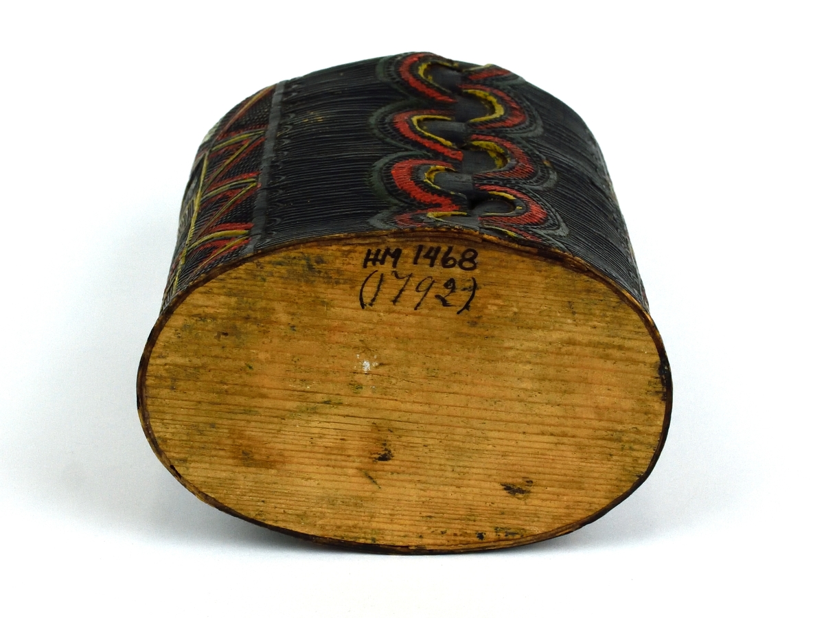 Förmodligen en tobaksburk. Burken är tillverkad av svept, tampad näver med botten av trä. Den har ristad dekoration runt om samt är målad i flera färger. Lock saknas.