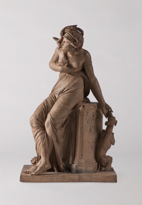 Den trofasta vänskapen (La fidèle Amitié), utförd år 1795 av den franske konstnären Jean-Baptiste Stouf (1742-1826) och utställd på Salongen i Paris samma år. Konstnären var nära vän till Johan Tobias Sergel under studieåren i Rom mer än två decennier tidigare. Stoufs verk är ett ypperligt exempel på den franska nyklassicismen där antikiserande formideal blandas med svärmisk vänskapskult. Skulpturen visar en kvinna, klädd à l’antique, som lutar sig mot vänskapens och kärlekens altare, vaktat av en hund, symbolen för trohet. Sin högra hand har hon fört mot hjärtat samtidigt som en duva, kärlekens symbol, satt sig på axeln och krönt henne med en krans av blommor från ett granatäppelträd. Det sistnämnda får representera äktenskapet.Även om motivet för skulpturen anpassar sig till den franska klassicismens förtjusning i högstämda ämnen, finns här samtidigt ett berättande, litterärt drag genom de många syftningar på olika antika gudasagor med kärlekspar såsom Herkules och Omfale eller Flora och Sefyr. I Stoufs allegoriska komposition blir den unga kvinnan en sinnebild för vänskapen. Hennes sentimentala och lätt dramatiska pose bidrar samtidigt till verkets genreartade karaktär, som är typisk för konstnärens arbeten under revolutionstiden.Den fina och mjuka modelleringen av i synnerhet kvinnans hud visar att terrakottaskulpturen Den trofasta vänskapen inte skall betraktas som en skiss utan som ett fullbordat, autonomt verk. Några andra versioner är heller inte kända. Presentationsterrakottan som fenomen sammanhänger med ett nytt mode under 1700-talet då samlare fascinerades av materialets konstnärliga uttryck. Det gav skulptören möjlighet att i mindre format visa prov på sin skaparkraft och tekniska skicklighet. Mest känd blev kanske Clodion för sina terrakottor, representerad i Nationalmuseum med två verk. I museets samling dominerar dock Sergels små skulpturer, som nu fått sällskap av vännen Stoufs Den trofasta vänskapen.Beskrivning som månadens nyförvärv, April 2013:Terrakottaskulptur av Jean-Baptiste Stouf Nationalmuseums samlingar har utökats med en terrakottaskulptur, kallad Den trofasta vänskapen (La fidèle Amitié), utförd år 1795 av den franske konstnären Jean-Baptiste Stouf (1742-1826) och utställd på Salongen i Paris samma år. Konstnären var nära vän till Johan Tobias Sergel under studieåren i Rom mer än två decennier tidigare. Stoufs verk är ett ypperligt exempel på den franska nyklassicismen där antikiserande formideal blandas med svärmisk vänskapskult. Skulpturen visar en kvinna, klädd à l’antique, som lutar sig mot vänskapens och kärlekens altare, vaktat av en hund, symbolen för trohet. Sin högra hand har hon fört mot hjärtat samtidigt som en duva, kärlekens symbol, satt sig på axeln och krönt henne med en krans av blommor från ett granatäppelträd. Det sistnämnda får representera äktenskapet.Även om motivet för skulpturen anpassar sig till den franska klassicismens förtjusning i högstämda ämnen, finns här samtidigt ett berättande, litterärt drag genom de många syftningar på olika antika gudasagor med kärlekspar såsom Herkules och Omfale eller Flora och Sefyr. I Stoufs allegoriska komposition blir den unga kvinnan en sinnebild för vänskapen. Hennes sentimentala och lätt dramatiska pose bidrar samtidigt till verkets genreartade karaktär, som är typisk för konstnärens arbeten under revolutionstiden.Den fina och mjuka modelleringen av i synnerhet kvinnans hud visar att terrakottaskulpturen Den trofasta vänskapen inte skall betraktas som en skiss utan som ett fullbordat, autonomt verk. Några andra versioner är heller inte kända. Presentationsterrakottan som fenomen sammanhänger med ett nytt mode under 1700-talet då samlare fascinerades av materialets konstnärliga uttryck. Det gav skulptören möjlighet att i mindre format visa prov på sin skaparkraft och tekniska skicklighet. Mest känd blev kanske Clodion för sina terrakottor, representerad i Nationalmuseum med två verk. I museets samling dominerar dock Sergels små skulpturer, som nu fått sällskap av vännen Stoufs Den trofasta vänskapen.