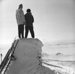 To damer står på et snødekt sylinder-formet byggverk. Jenny 