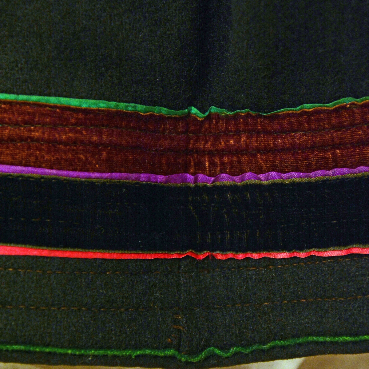 Fra protokoll: Kvindedragt, oprindelig syet som brudedragt, bestående av A. Sort stakk av vadmel med  fastsydd livstykke av rødt damask; foran paa dette 12 maler med skaaler.
Kvinnedrakten har flere deler: Trøye, forkle, belte, sokker og sko :TGM-BM.1915:002.A-F 

Livstykket har 6 maler (filigran) på hver side. Hovedtøyet er av damask, silkefløyel rundt ermutringningene, broderiborder i blått og lilla bånd. Fòret er av hvitt bomullstøy. Livstykket er slitt. Stakken er av sort vadmel. Foran er det åpning med bånd på hver side. I sidesømmen er det påmontert en lomme innvendig av bomullstøy. Vadmelstøyet har flere hull, antageligvis angrepet av møll. Skoningen er 6 cm, under er det rødt ulltøy.  Dekor på skoningen er 3 smale bånd i grønn, lilla og rosa. Videre er det 2 bredere fløyelsbånd i  burgunder og sort. Skoningen er slitt på flere områder.