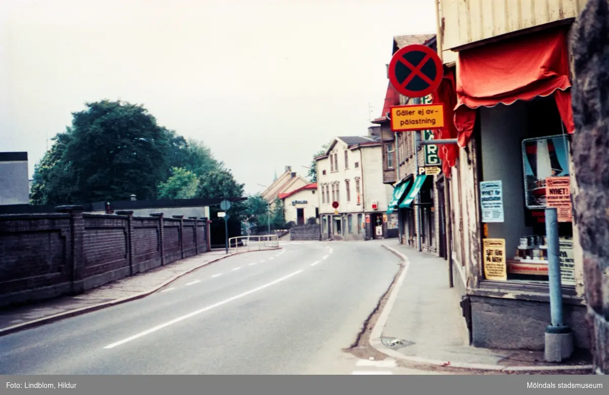 Bebyggelse vid Kvarnbygatan i Mölndal, 1970-tal. På höger sida av gatan ses från höger fastigheterna Kvarnbygatan 27, 25, 23 och längst ned nr 21. På vänster sida Papyrus mur.

För mer information om bilden se under tilläggsinformation.