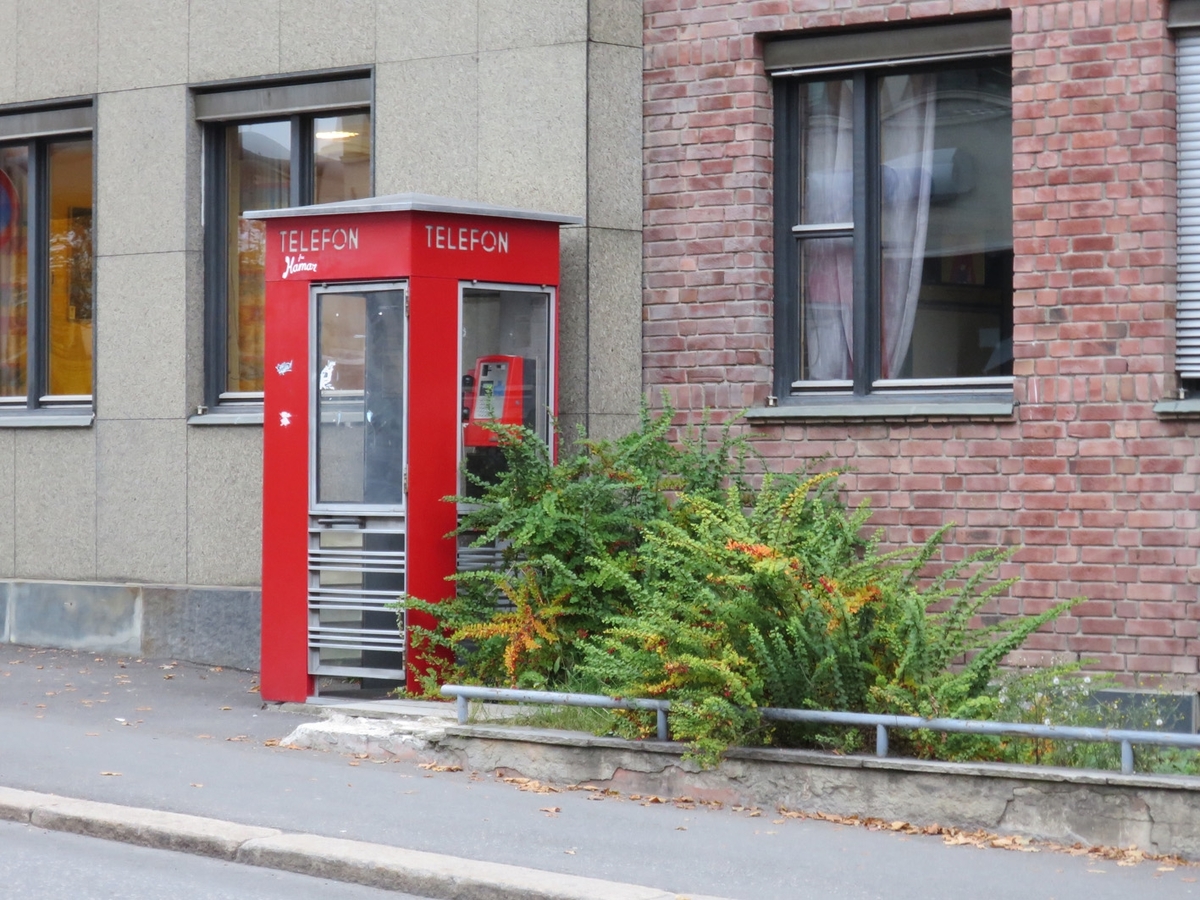 Denne telefonkiosken står i Kirkegata 45, Lillehammer, og er en av de 100 vernede telefonkioskene i Norge. De røde telefonkioskene ble laget av hovedverkstedet til Telenor (Telegrafverket, Televerket). Målene er så å si uforandret. 
Vi har dessverre ikke hatt kapasitet til å gjøre grundige mål av hver enkelt kiosk som er vernet. 
Blant annet er vekten og høyden på døra endret fra tegningene til hovedverkstedet fra 1933.
Målene fra 1933 var:
Høyde 2500 mm + sokkel på ca 70 mm
Grunnflate 1000x1000 mm.
Vekt 850 kg.
Mange av oss har minner knyttet til den lille røde bygningen. Historien om telefonkiosken er på mange måter historien om oss.  Derfor ble 100 av de røde telefonkioskene rundt om i landet vernet i 1997. Dette er en av dem.