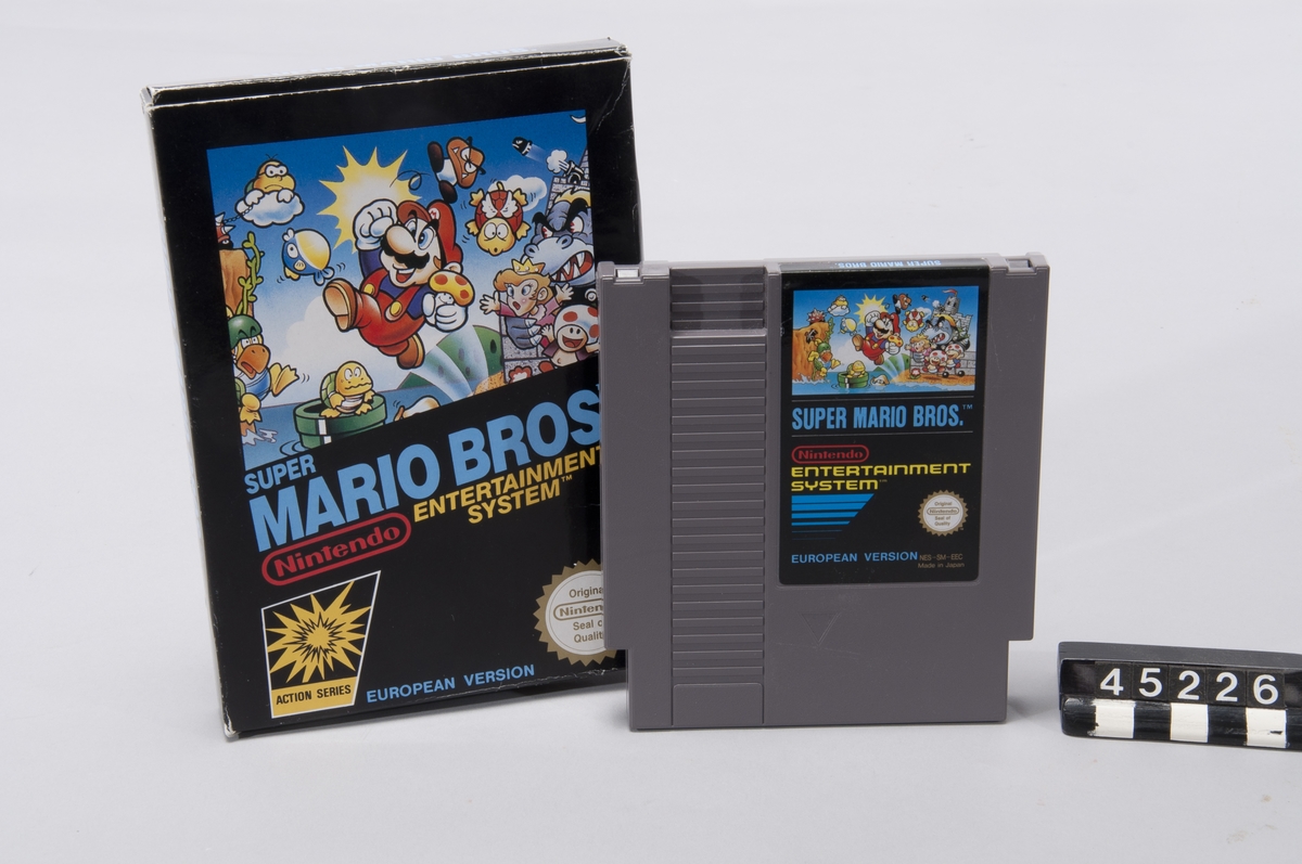 Cartridge med tv-spelet Super Mario Bro's inklusive kartong.  Super Mario Bros var ett sidscrollande plattformsspel, något som infördes i och med spelkonsolen NES vilket gjorde att spelvärlden kändes nästintill oändlig i jämförelse med de statiska spelplaner som tidigare spelkonsoler kunde hantera.  Spelet bestod av 8 världar med 4 banor i var värld.