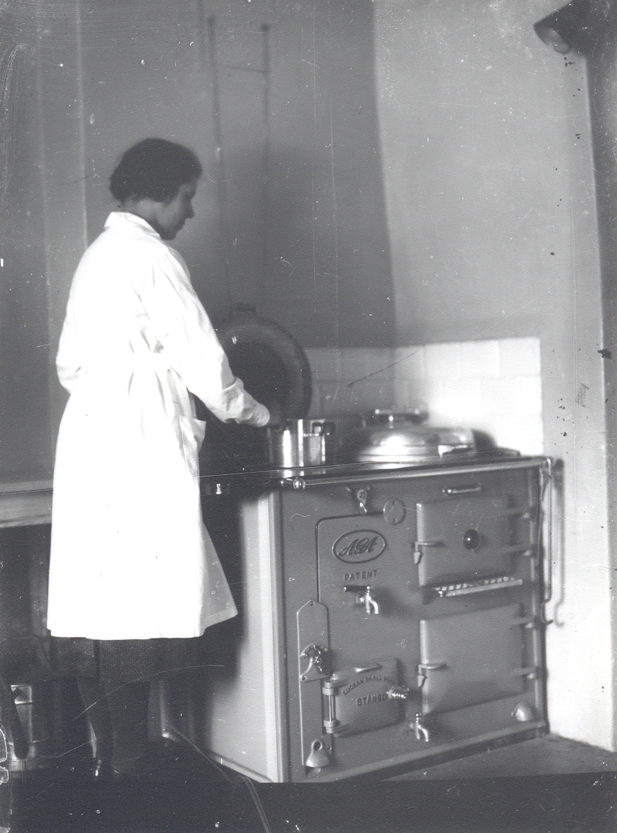 Therese Åström, kokerska hos doktor Magnusson i arbete vid den nyinstallerade AGA-spisen. Denna spis var den första AGA-spis som installerades i Mörtfors.