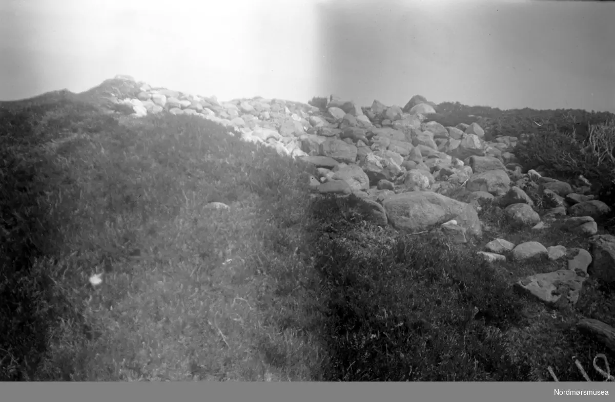 På bildet ser vi en gravrøys nord for Edøyvalens havbukt, nær Kulisvaet på Edøy. Se Yderstads notater, Bind 7. side 346, nummer 9. Bildet er datert Juni 1948, og mest sannsynlig den 16. denne måned. Nordmøre Museums samling