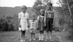 Fire barn på linje ute i en hage. Dette er trolig på Solbakk