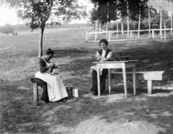 Foto av to kvinner som sitter ute i en hage.
Den ene i
 gang