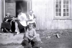 Foto av tre kvinner og en gutt sittende ute på ei
trapp fora