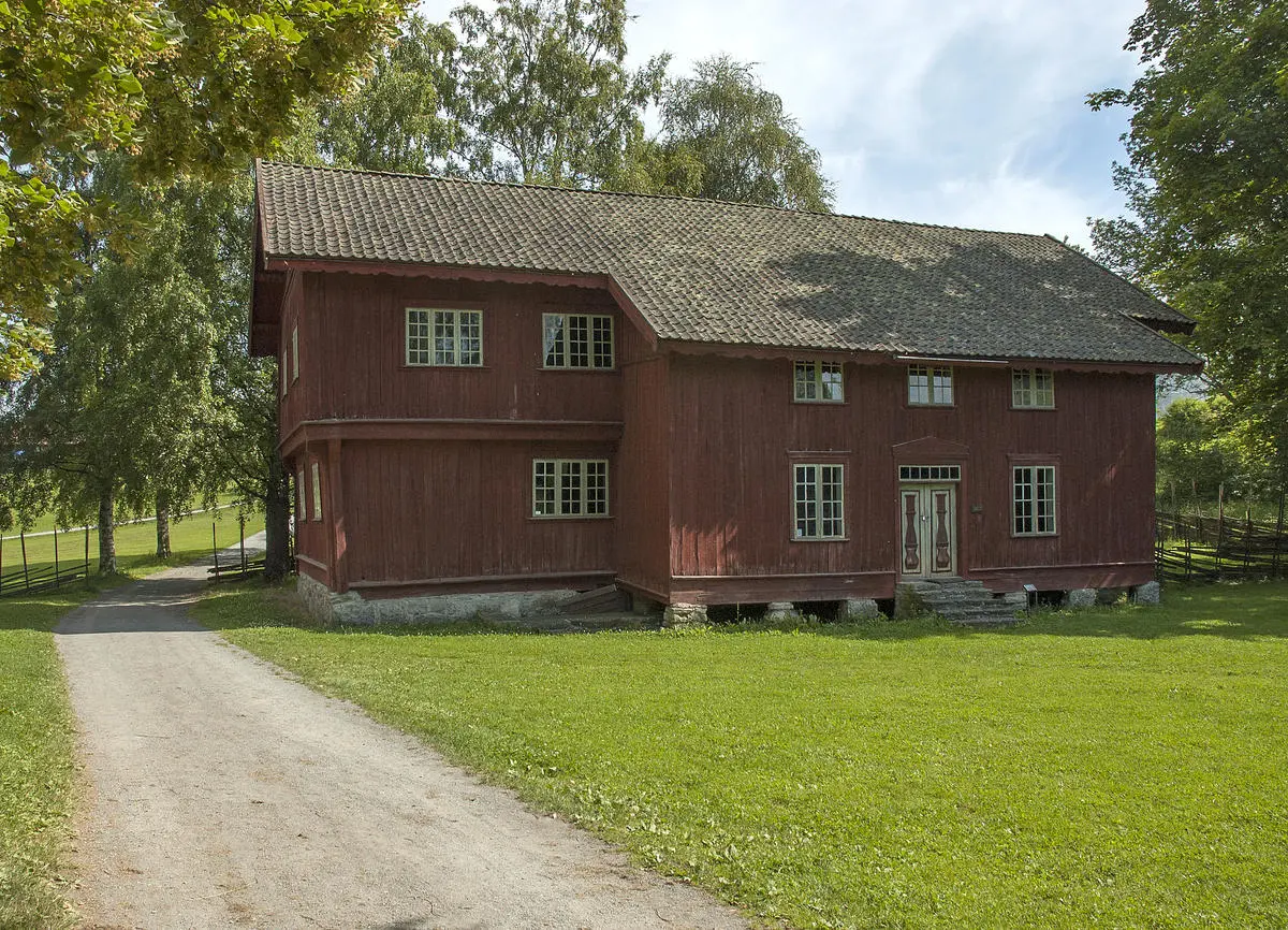Stor, rød, plankebeslått bygning i to etasjer.