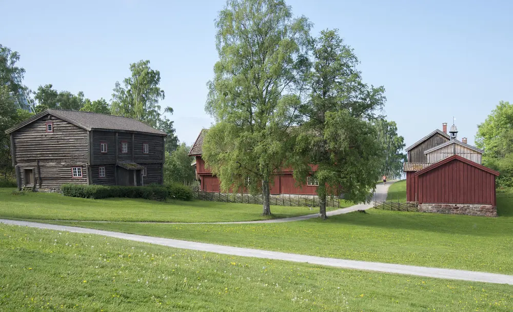 A log house and a red wooden house are part of the open air museum.