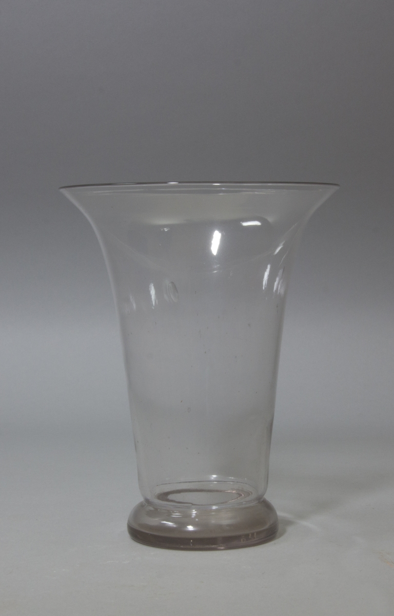 Blomglas i bägarform med utvikt mynning. Klart glas.