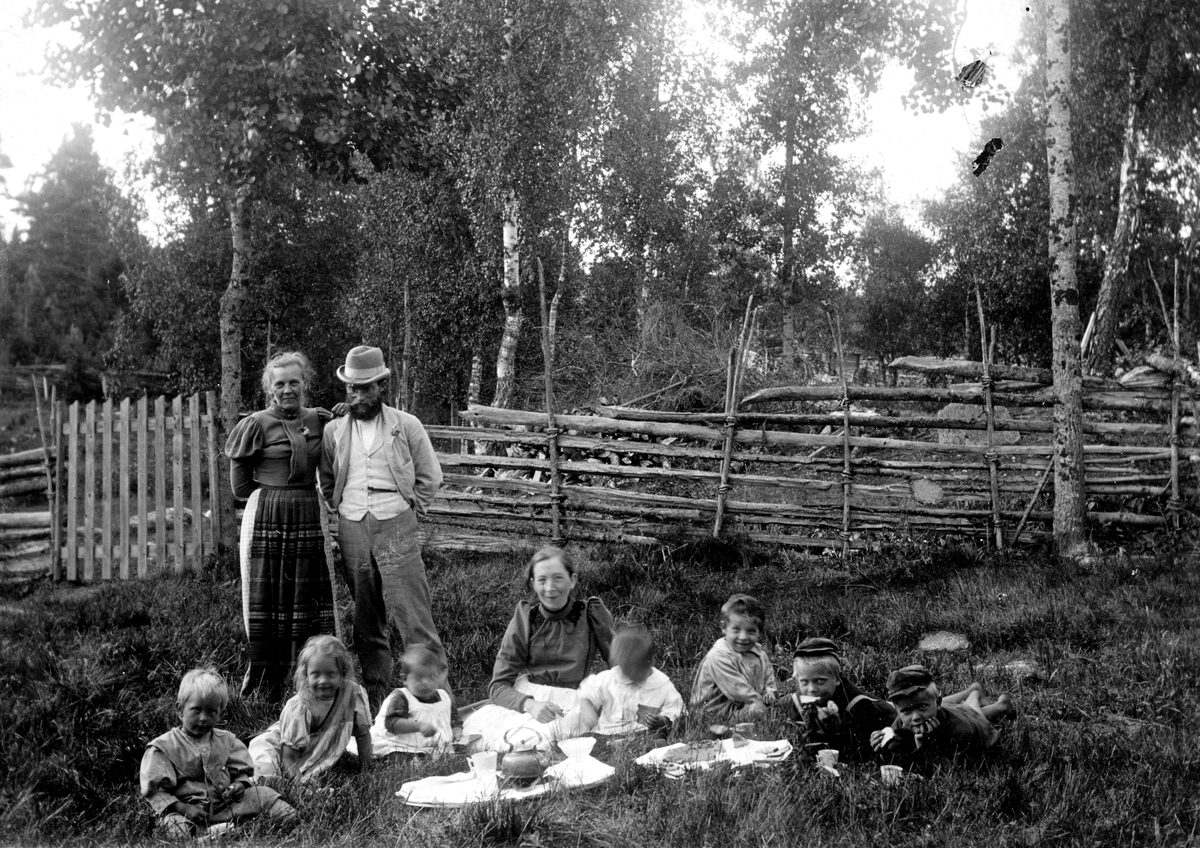 Två kvinnor och en man. Sju barn i en hage med kaffebricka. Fotograf Alfred Bergendahl. Givare H Bergendahl.