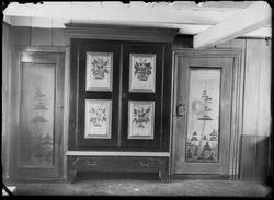 Interiør med et bemalt skap og to bemalte dører