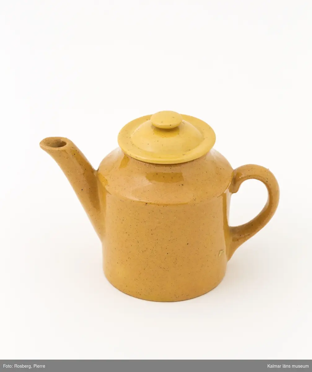 KLM 9792:2 Kanna, kaffekanna med lock. Av gult lergods, glaserat. Något ljusare gul ton på locket. Ingår i servis av lergods. Leksaksservis. Ostämplat. Tillverkat vid någon av Tillingegruppens fabrik under 1800-talets senare del.