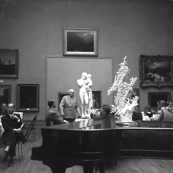 Sammankomst i tavelsalen på Smålands museum. Bl a syns en modell i gips "Dacke drömmer". Skulptören Carl Milles (1875-1955) talar.