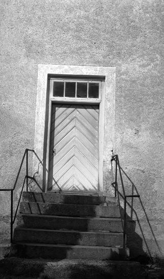 Foto av en kyrktrappa med en dörr bakom. 
Litt.: Smålandsposten 14/5 1932.