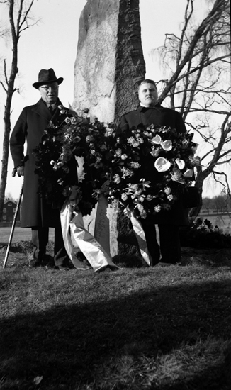 Foto på en kvinna och en man som står framför Per Henrik Lings minnessten med en krans i handen.
