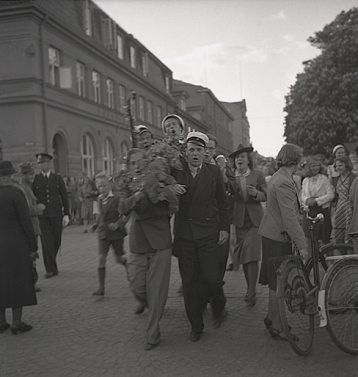 Studenterna, 1939. En student bärs fram längs Kungsgatan, söderut. I bakgrunden skymtar hörnet mot Storgatan (dåv. Skånska Banken, nuv. Adenmarks affär).