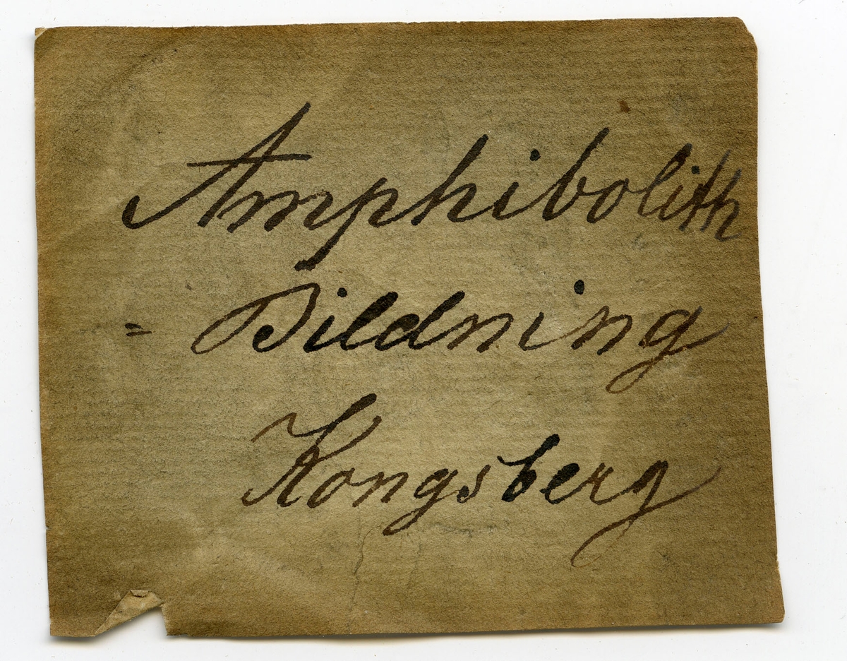 To etiketter i eske:
Etikett 1:
Amphibolith
- Bildning
Kongsberg

Etikett 2:
Amfibolit
Dronningens grube ved Dronningkollen