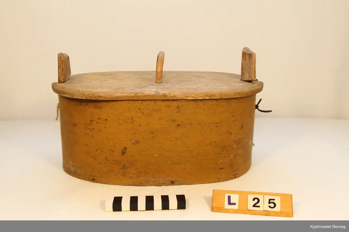 Oval utforming. Laupen har lokk som er innfelt i to trestykker som er festet i siden på laupen, hvor det ene trestykket er dreibart, og utgjør feste for lokket.