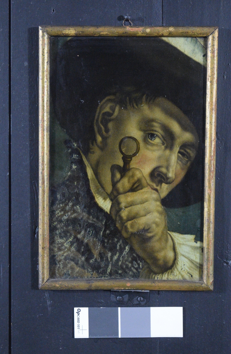 Bildet viser en mann som studerere noe gjennom en lupe. det virker som om han også har øyekontakt med betrakteren Forkortningene i bildet kan tyde på at det opprinnelig kan være tegnet ved hjelp av camera obscura.
