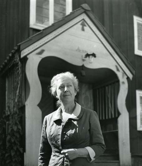 En kvinna poserar framför en byggnad med förstukvist.